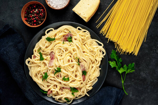 spaghetti carbonara with bacon and cheese on plate on black background