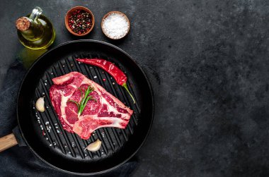 Baharatlı çiğ et ve siyah arka planda otlar.