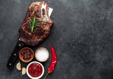 Baharatlı, sebzeli ve otlu ızgara biftek. Kesme bıçağında, koyu arka planda..