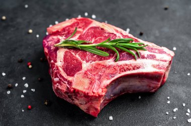 Baharatlı çiğ et ve siyah arka planda otlar.