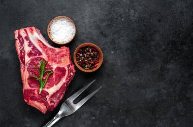 Baharatlı çiğ et ve siyah arka planda otlar.