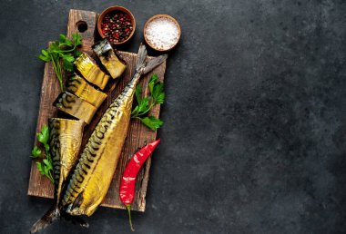 Ahşap bir ozanda baharat ve şifalı taze füme balık. Koyu arkaplan