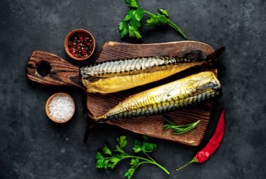 Ahşap bir ozanda baharat ve şifalı taze füme balık. Koyu arkaplan