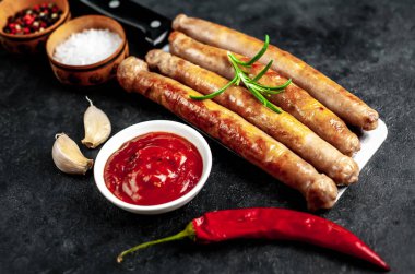 Baharatlı, sebzeli ve otlu ızgara sosisler siyah arka planda bir satır bıçağında..