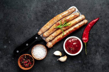 Baharatlı, sebzeli ve otlu ızgara sosisler siyah arka planda bir satır bıçağında..