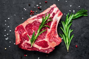 Baharatlı çiğ et ve siyah arka planda otlar.