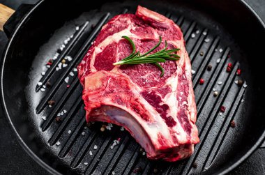 Baharatlı çiğ et ve siyah arka planda otlar.