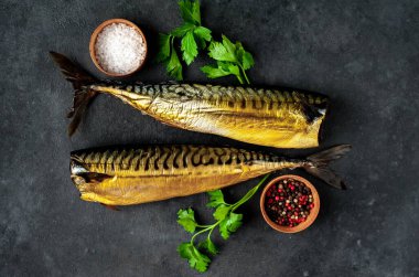 Esmer arka planda baharat ve otlarla taze füme balık.