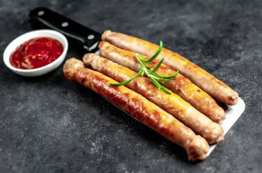 Baharatlı, sebzeli ve otlu ızgara sosisler siyah arka planda bir satır bıçağında..