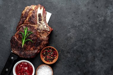Baharatlı, sebzeli ve otlu ızgara biftek. Kesme bıçağında, koyu arka planda..