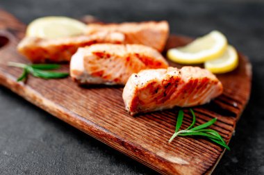 Limon dilimli baharatlı ızgara somon parçaları ve koyu arkaplanda biberiye. 