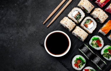 Farklı suşi dürümleri ve siyah arka planda nigiri suşisi.