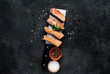 Koyu arkaplanda baharatlı ızgara somon parçaları. 