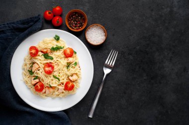 Soslu, sebzeli ve siyah arka planda etli makarna tabağı.