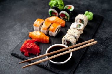 Yan görünüş, soya sosu ve yemek çubuklarıyla çeşitli suşi setlerinin yakın çekimi.