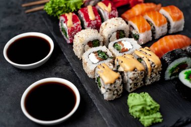 Yan görünüş, soya sosu ve yemek çubuklarıyla çeşitli suşi setlerinin yakın çekimi.