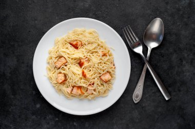 Soslu, sebzeli ve siyah arka planda etli makarna tabağı.