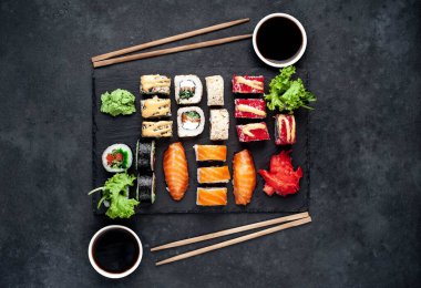 Soya sosu ve yemek çubuklarıyla sıralanmış suşi setinin üst görüntüsünü kapat.