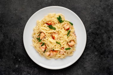 Soslu, sebzeli ve siyah arka planda etli makarna tabağı.