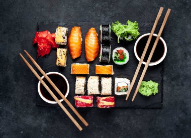 Soya sosu ve yemek çubuklarıyla sıralanmış suşi setinin üst görüntüsünü kapat.
