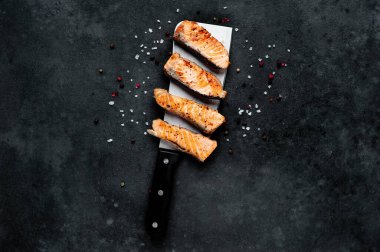 Satırda ızgara somon parçaları ve arka planda baharatlar. 