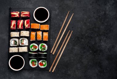 Farklı suşi dürümleri ve siyah arka planda nigiri suşisi.