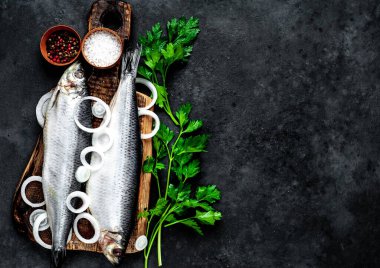 Tahtada soğan, baharat ve maydanozla marine edilmiş uskumrular.