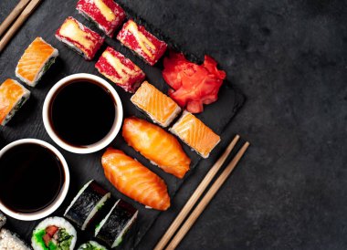 Soya sosu ve yemek çubuklarıyla sıralanmış suşi setinin üst görüntüsünü kapat.
