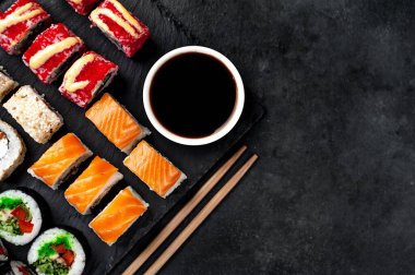 Farklı suşi dürümleri ve siyah arka planda nigiri suşisi.