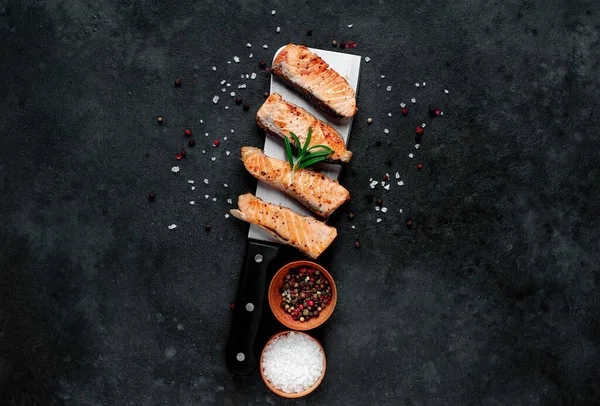 Koyu arkaplanda baharatlı ızgara somon parçaları. 