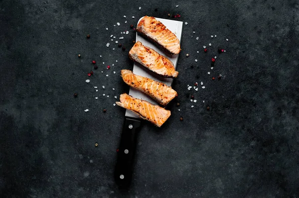 Satırda ızgara somon parçaları ve arka planda baharatlar. 