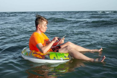 Suda şişme yüzük tabletli bir adam.