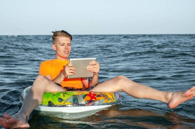 Suda şişme yüzük tabletli bir adam.