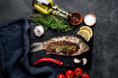 Limonlu ve biberiyeli sazan balığı. Taş zeminde bir tahta üzerinde.