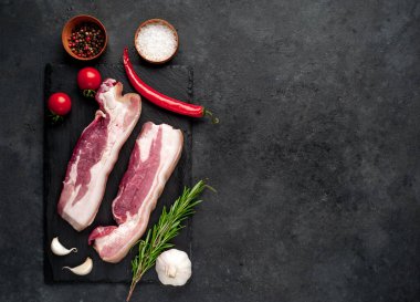 Metnin için fotokopi alanı olan taştan bir arka planda kesilmiş baharatlı çiğ domuz göğsü.