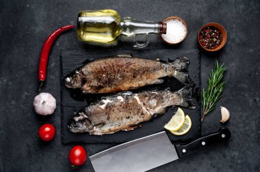 Taş zeminde baharat ve malzemelerle kızarmış balık alabalığı.