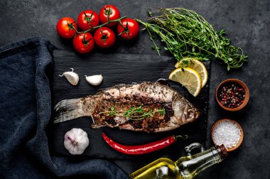 Limonlu ve biberiyeli sazan balığı. Taş zeminde bir tahta üzerinde.