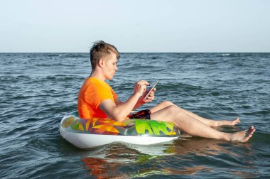 Suda şişme yüzük tabletli bir adam.