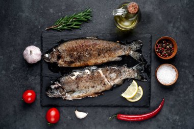 Taş zeminde baharat ve malzemelerle kızarmış balık alabalığı.