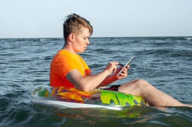 Suda şişme yüzük tabletli bir adam.