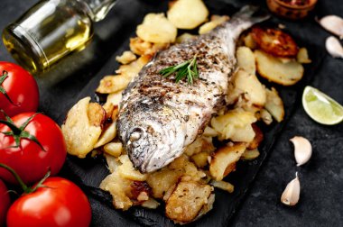 Kayalık zeminde kızarmış Dorado balığı ve patates.