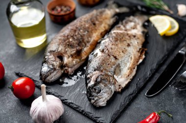 Taş zeminde baharat ve malzemelerle kızarmış balık alabalığı.