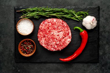 Biberiyeli çiğ hamburger köftesi ve arka planda baharatlar