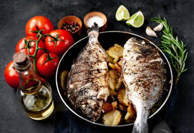 Kayalık zeminde kızarmış Dorado balığı ve patates.