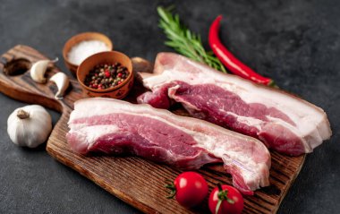 Metnin için fotokopi alanı olan taştan bir arka planda kesilmiş baharatlı çiğ domuz göğsü.