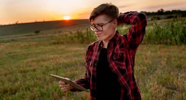 Tarlada gün batımında tabletli çiftçi, tarım yönetimi kavramı