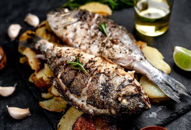 Kayalık zeminde kızarmış Dorado balığı ve patates.