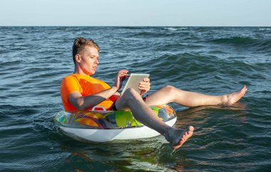 Suda şişme yüzük tabletli bir adam.