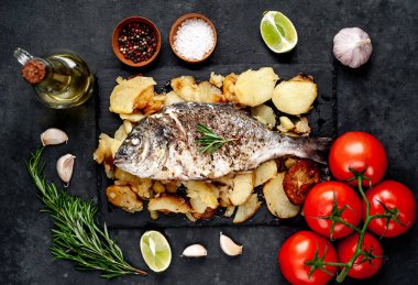 Kayalık zeminde kızarmış Dorado balığı ve patates.