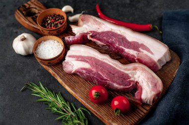 Metnin için fotokopi alanı olan taştan bir arka planda kesilmiş baharatlı çiğ domuz göğsü.